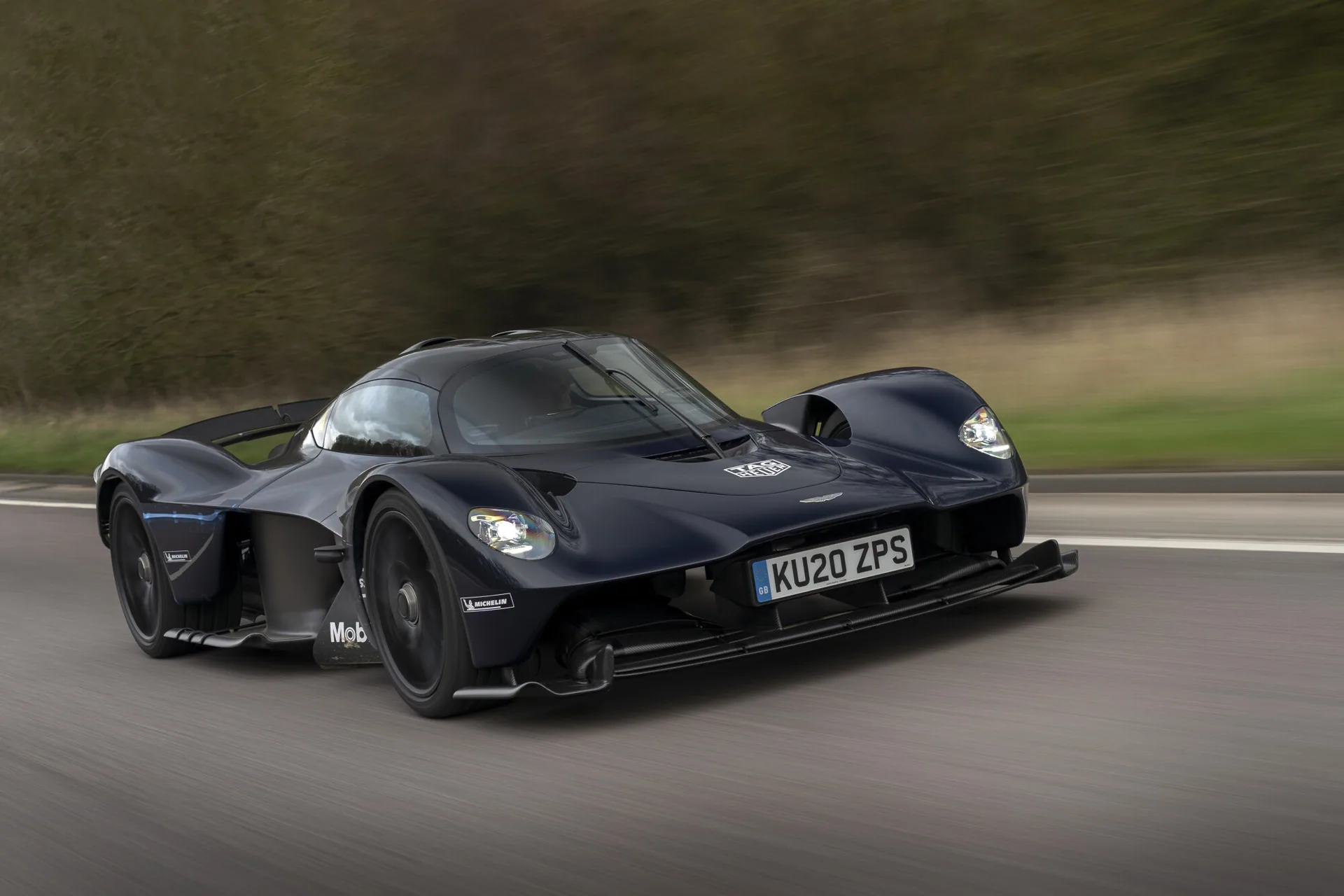 Sort Aston Martin Valkyrie med britiske nummerplader i fart på en landevej