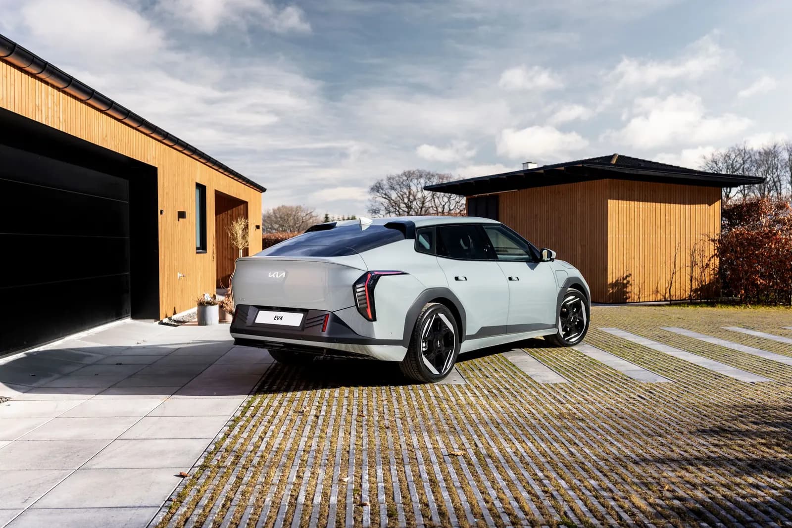 Lysegrå Kia EV4 set fra siden foran en rødbrun bygningsfacade